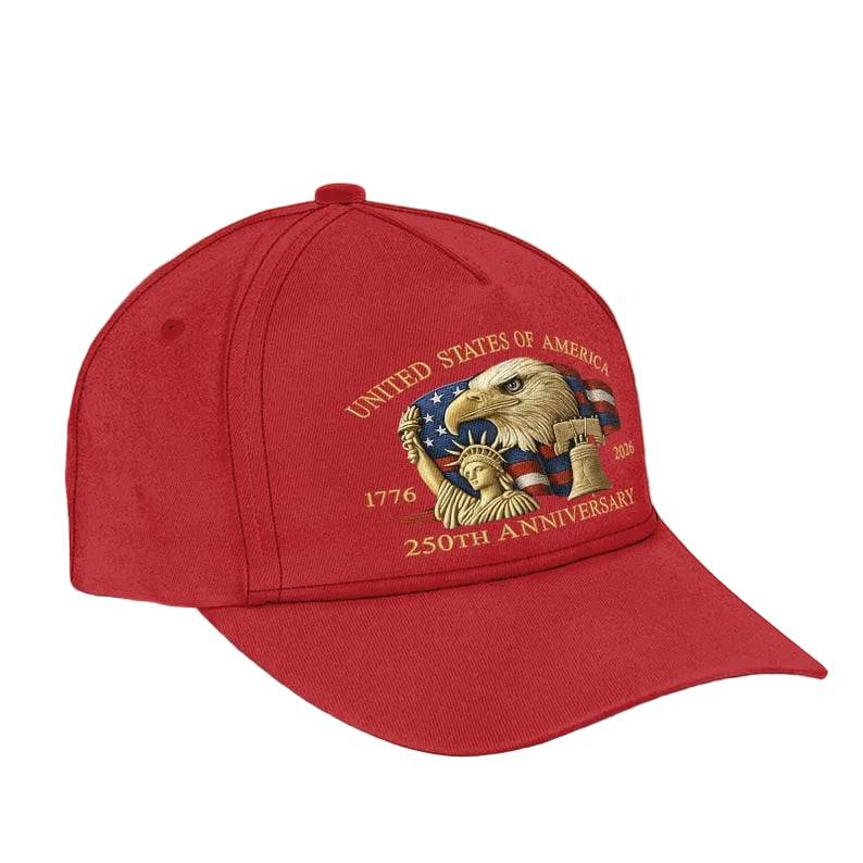 Red cap with 'United States of America 250th Anniversary' design on a wooden surface with blurred lights in the background